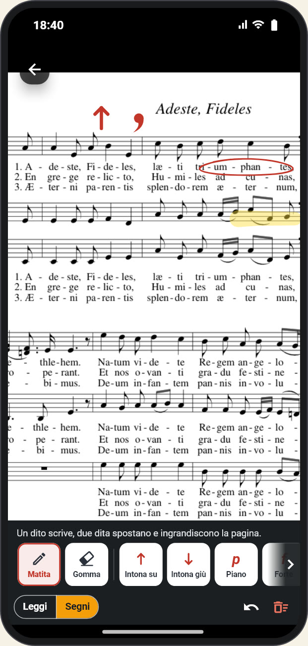Lo spartito di «Adeste, Fideles» in Coralis con la matita in mano: «tri-um-phan-tes» cerchiato in rosso, un respiro e una freccia «Intona su» sopra il rigo, alcune note evidenziate in giallo; in basso la barra della matita